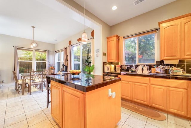 kitchen featuring light brown cabinets, a kitchen island, hanging light fixtures, and a wealth of natural light