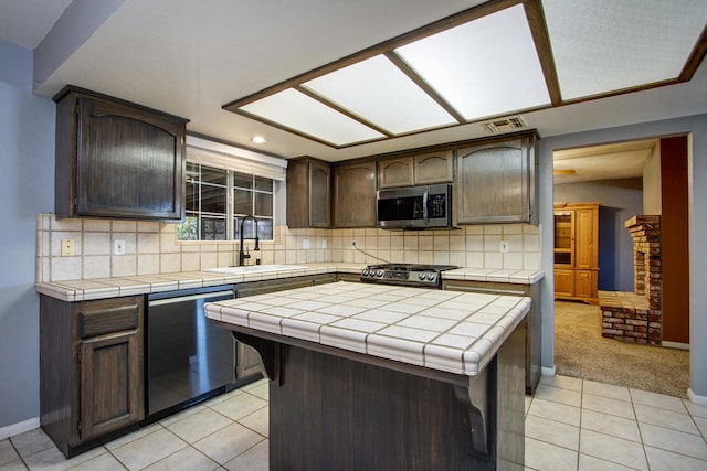 kitchen with appliances with stainless steel finishes, tile countertops, sink, and tasteful backsplash