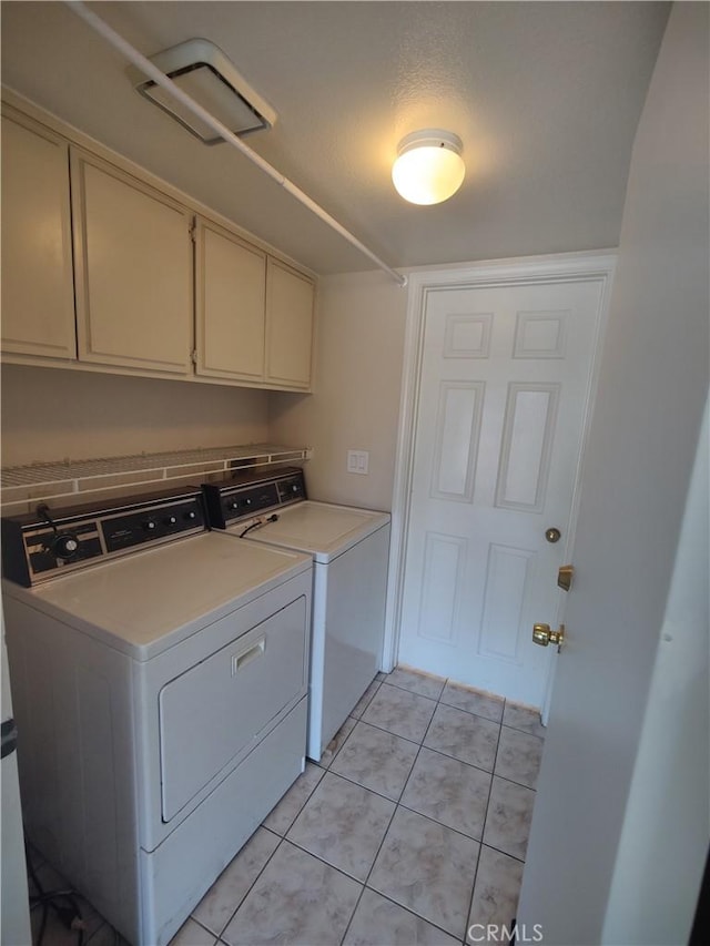 laundry room with washer and clothes dryer, light tile patterned floors, and cabinets