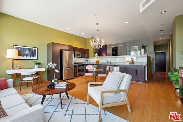 living room featuring light wood-type flooring, a chandelier, and sink