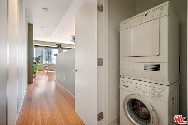 laundry area with stacked washer and dryer and light hardwood / wood-style floors