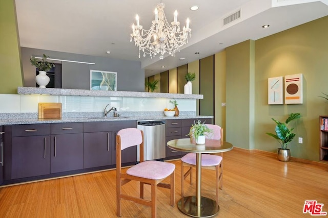 kitchen featuring light hardwood / wood-style flooring, light stone countertops, a notable chandelier, sink, and stainless steel dishwasher