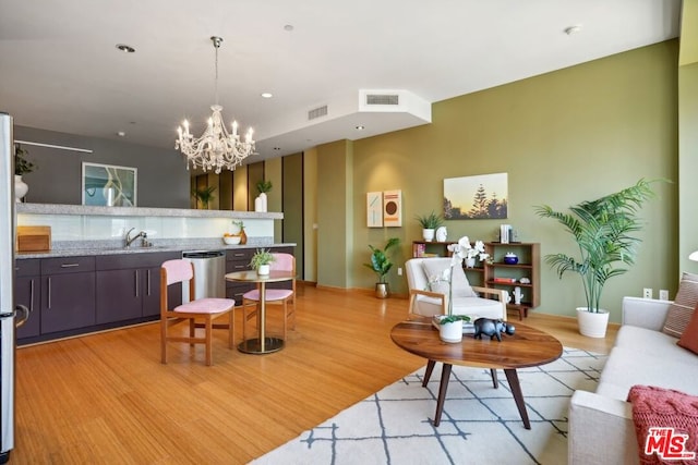 living room with light hardwood / wood-style flooring, sink, and a notable chandelier