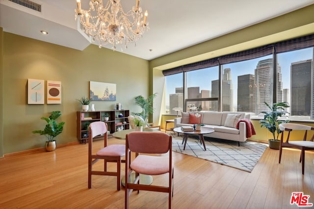 living room with a wealth of natural light, an inviting chandelier, and light hardwood / wood-style flooring