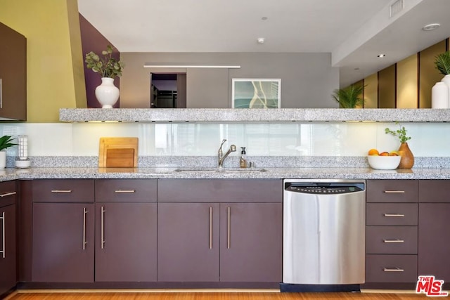 kitchen with dishwasher, sink, light stone countertops, and light wood-type flooring