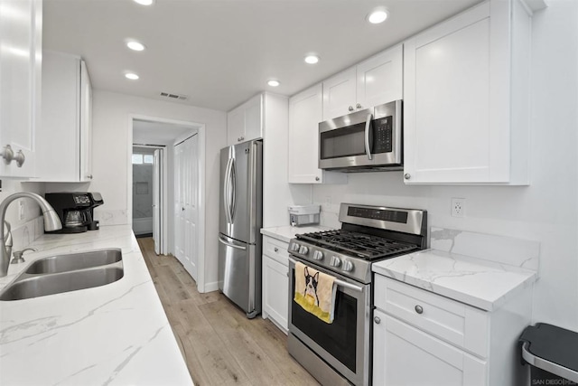 kitchen featuring sink, appliances with stainless steel finishes, light stone counters, and light hardwood / wood-style floors