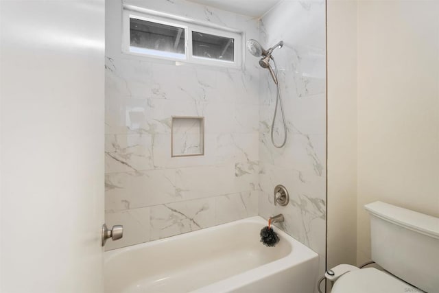 bathroom with toilet and tiled shower / bath