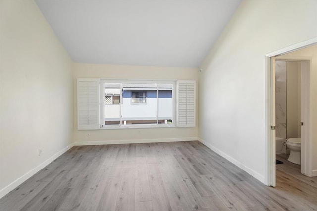 spare room with light wood-type flooring and vaulted ceiling