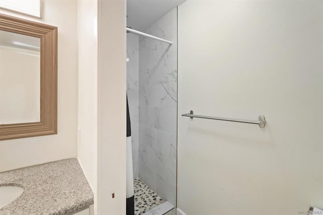 bathroom featuring a tile shower and vanity