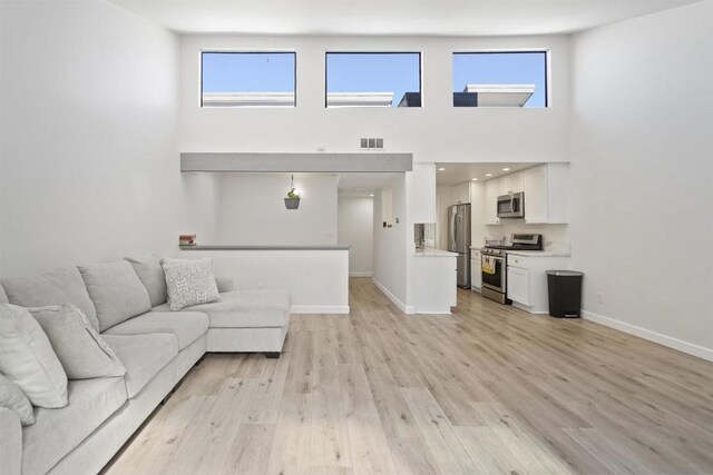 unfurnished living room with light wood-type flooring and a high ceiling