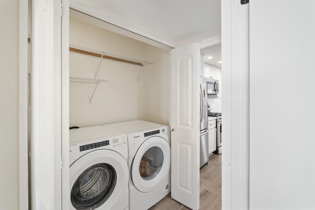 clothes washing area featuring light wood-type flooring and washer and dryer