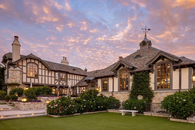 back house at dusk with a lawn