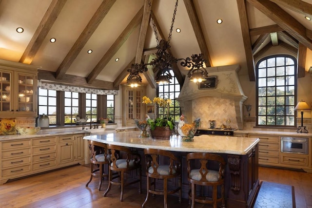 kitchen with a spacious island, stainless steel oven, light stone countertops, and a healthy amount of sunlight