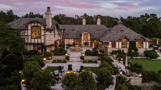 view of front of house with a lawn, a patio, and a fire pit