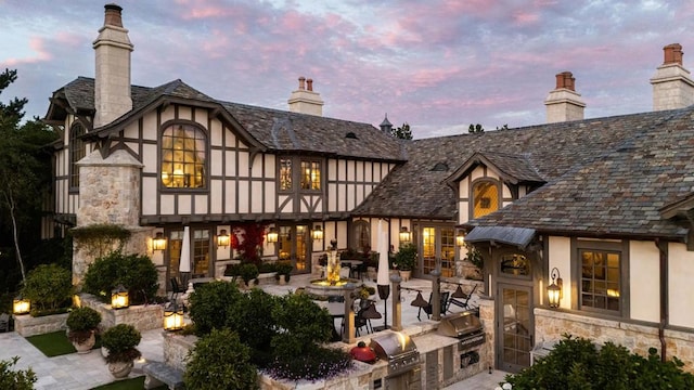 back house at dusk with a patio and area for grilling