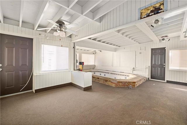 unfurnished bedroom with carpet floors, beamed ceiling, and ceiling fan