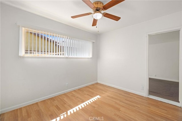 empty room with a ceiling fan, baseboards, and wood finished floors