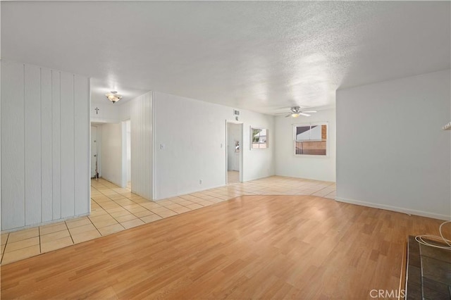 empty room with a ceiling fan, a textured ceiling, and light tile patterned floors