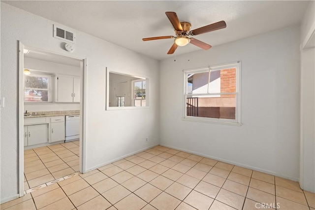 unfurnished room featuring light tile patterned floors, visible vents, a ceiling fan, a sink, and baseboards