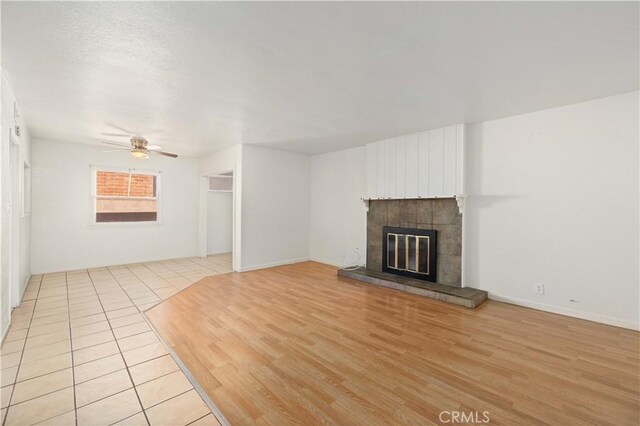 unfurnished living room featuring ceiling fan, a fireplace, and light hardwood / wood-style flooring