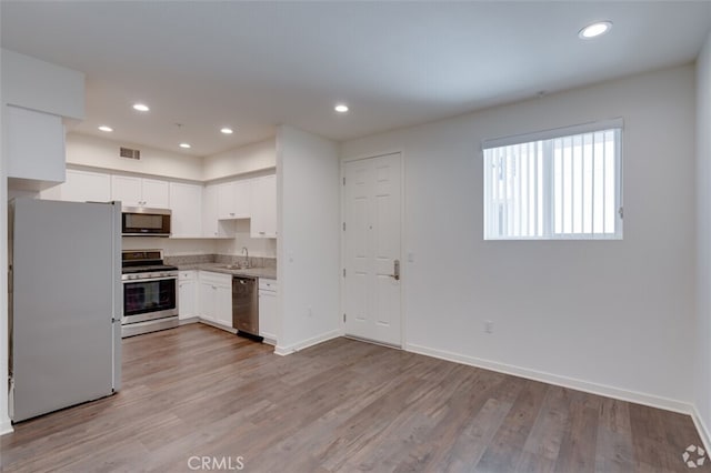 kitchen featuring sink, stainless steel appliances, white cabinetry, and light hardwood / wood-style flooring