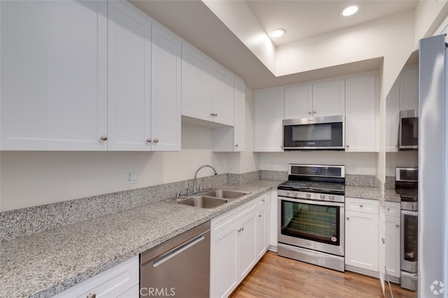 kitchen featuring light hardwood / wood-style flooring, white cabinetry, light stone counters, sink, and stainless steel appliances