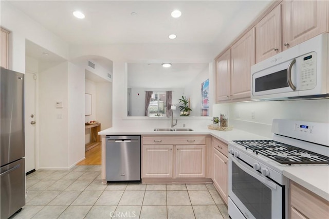 kitchen with light brown cabinetry, sink, stainless steel appliances, and light tile patterned flooring