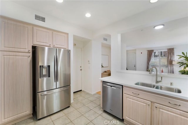 kitchen with light tile patterned floors, sink, light brown cabinets, and stainless steel appliances