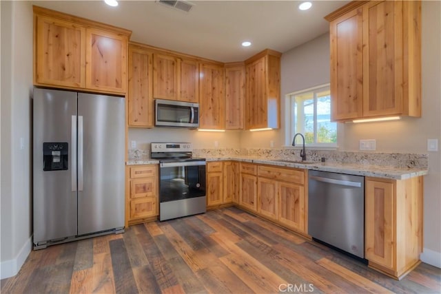 kitchen featuring sink, dark hardwood / wood-style flooring, light stone countertops, and appliances with stainless steel finishes