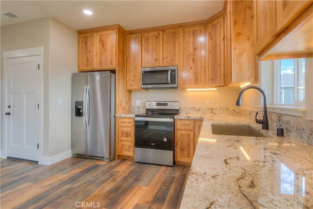 kitchen featuring stainless steel appliances, sink, light stone counters, and dark wood-type flooring