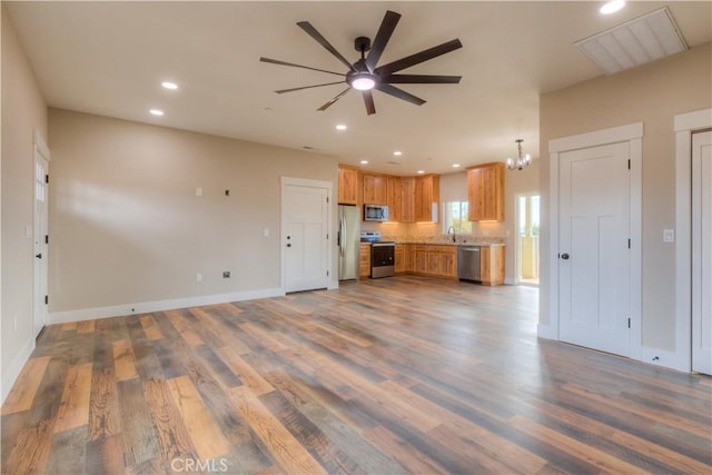 unfurnished living room with ceiling fan with notable chandelier and dark hardwood / wood-style floors