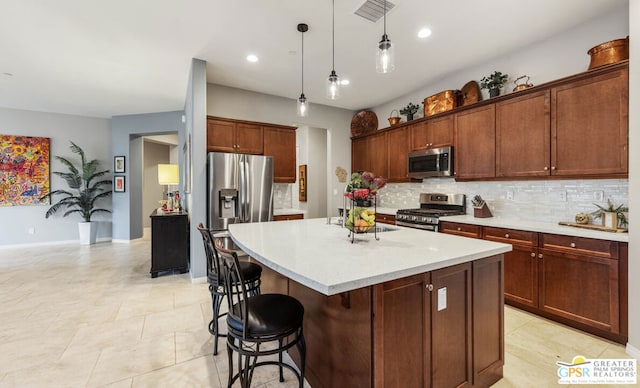 kitchen featuring hanging light fixtures, appliances with stainless steel finishes, backsplash, and a center island