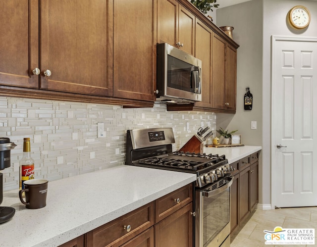 kitchen with light stone countertops, stainless steel appliances, and tasteful backsplash