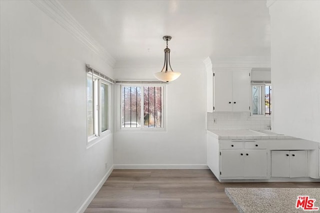 unfurnished dining area featuring light wood-type flooring and crown molding