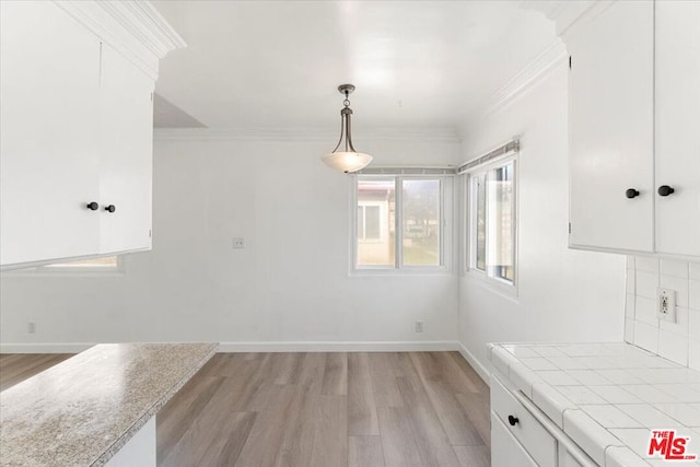 unfurnished dining area featuring light hardwood / wood-style flooring and crown molding