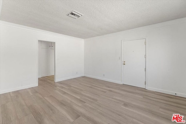 empty room featuring a textured ceiling, light hardwood / wood-style flooring, and ornamental molding