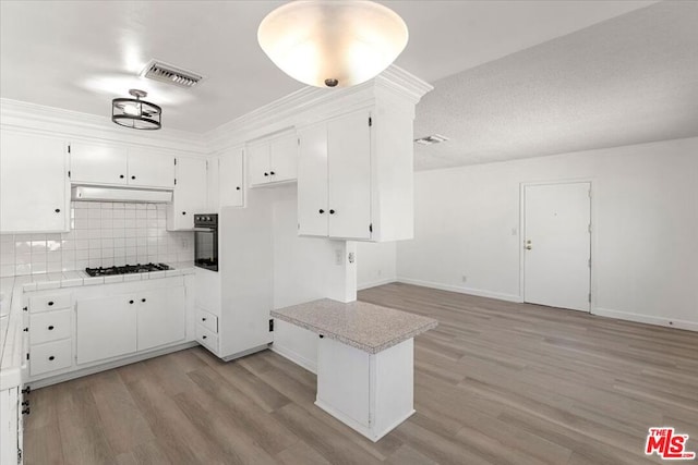 kitchen featuring light hardwood / wood-style flooring, white cabinets, tasteful backsplash, and oven