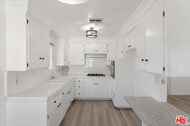 kitchen featuring white cabinetry, tile countertops, decorative backsplash, white gas cooktop, and sink