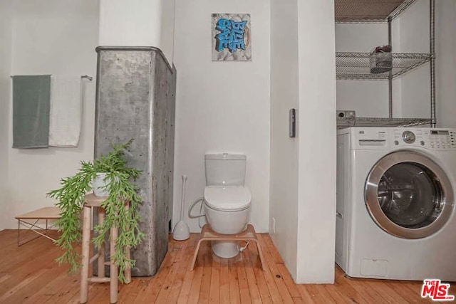 bathroom with wood-type flooring, washer / clothes dryer, and toilet