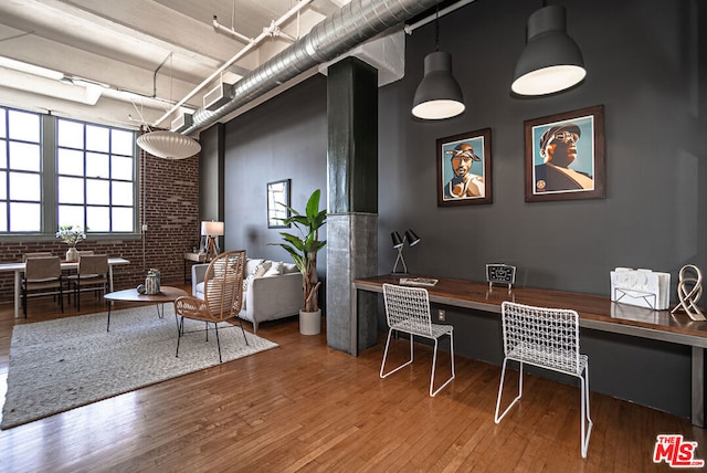 office area with hardwood / wood-style flooring and brick wall