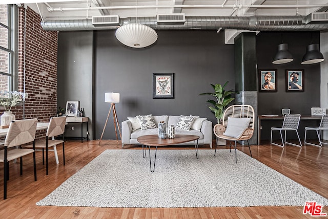 living room with hardwood / wood-style floors and brick wall