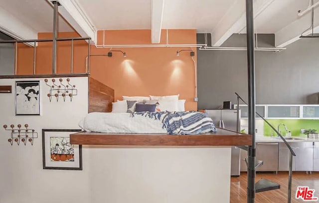 bedroom with hardwood / wood-style floors, sink, beamed ceiling, and stainless steel refrigerator