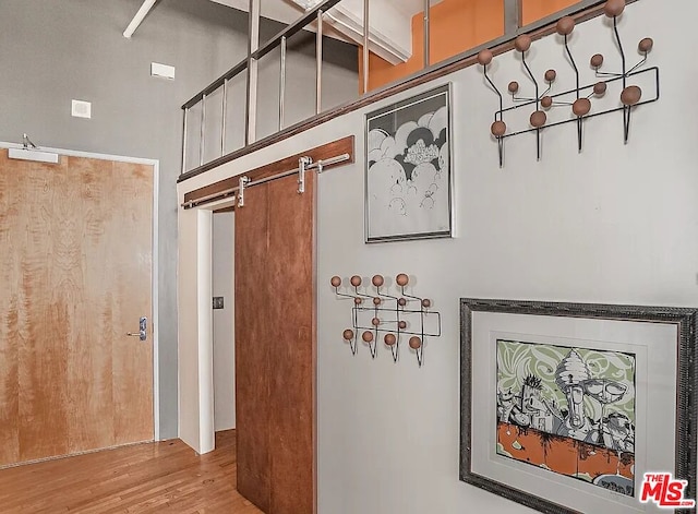 hallway with wood-type flooring, a barn door, and a high ceiling