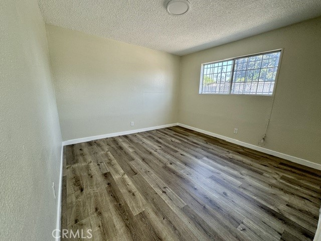 unfurnished room with a textured ceiling and hardwood / wood-style floors