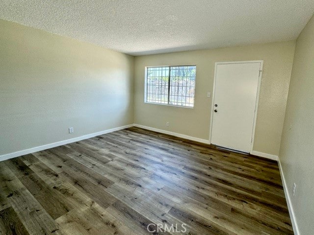 spare room with a textured ceiling and dark hardwood / wood-style floors