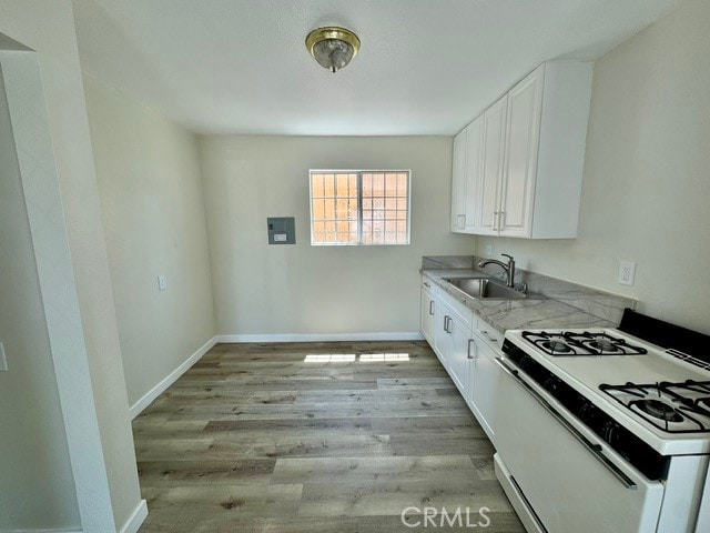 kitchen featuring white cabinets, sink, light hardwood / wood-style flooring, white gas stove, and light stone countertops