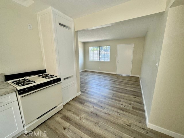 kitchen featuring light hardwood / wood-style flooring, white cabinetry, and white range with gas stovetop