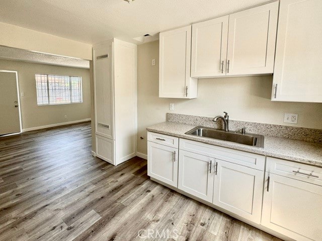 kitchen with light hardwood / wood-style floors, sink, and white cabinets