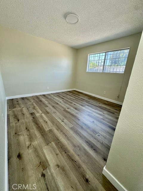 spare room with a textured ceiling and hardwood / wood-style floors