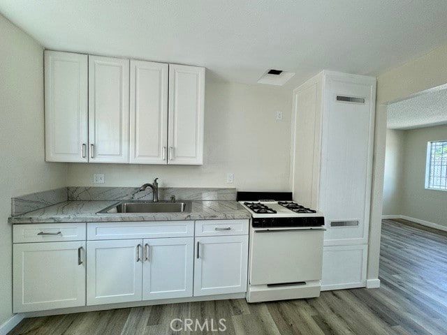 kitchen featuring white cabinets, sink, light hardwood / wood-style flooring, and gas range gas stove